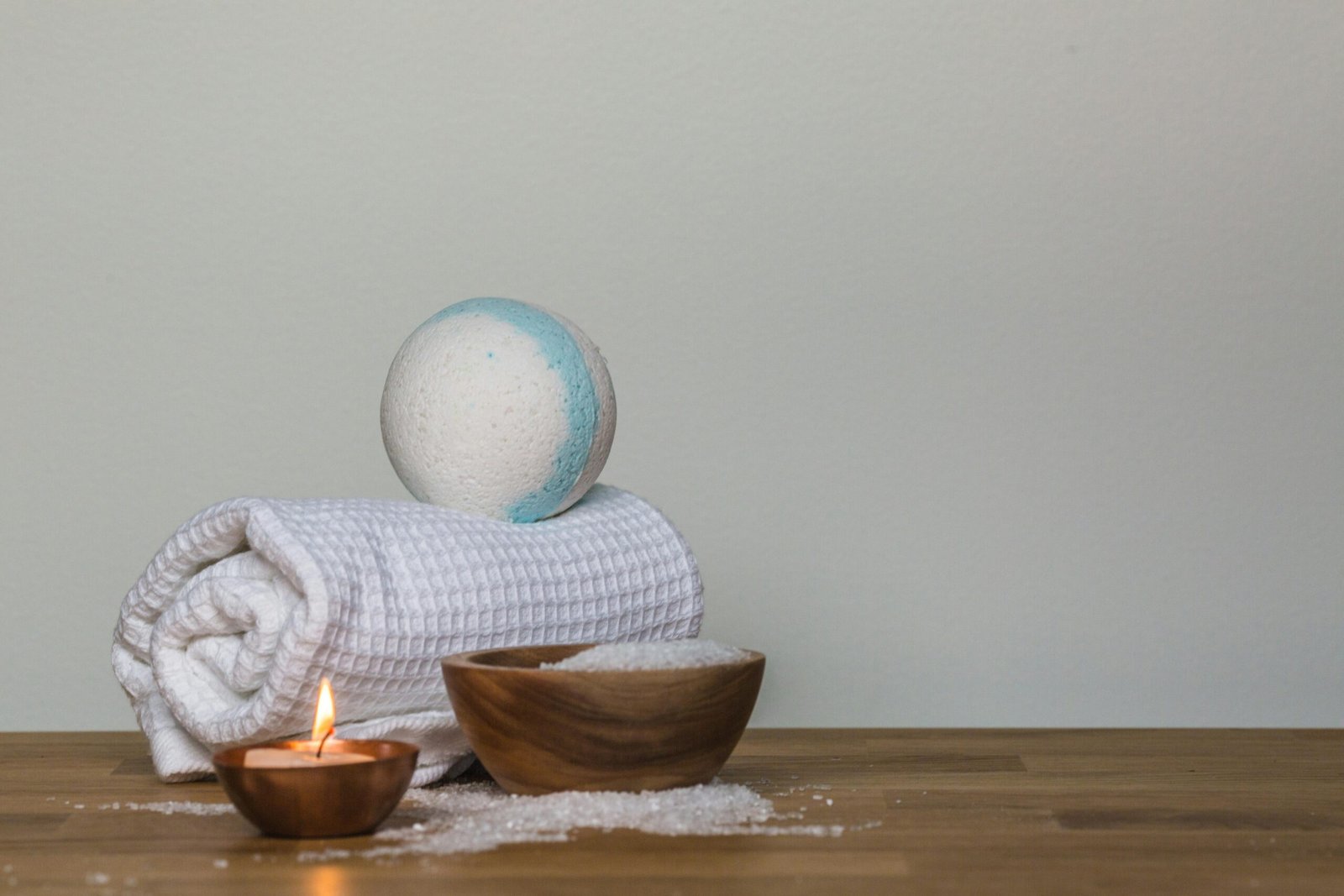 Peaceful spa setting with bath bomb, salt, candle, and towel, perfect for relaxation.